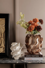 Decorative vase with flowers on a surface next to a Louis Vuitton book