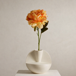 White vase with a single orange and yellow flower on a neutral background