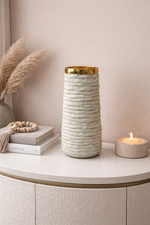 Decorative vase with gold rim on a shelf with books and a candle