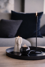Decorative candles on a black tray with a blurred sofa in the background