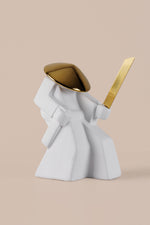 Minimalist white warrior sculpture with gold helmet and sword displayed as luxury home decor