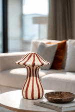 Decorative striped vase on a table with a blurred living room background