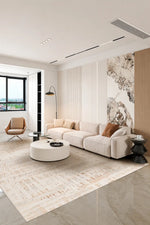 A modern living room featuring a light beige sectional sofa, a round white coffee table, a large textured beige rug, and a prominent vertical wall art mural with a black and white abstract pattern.
