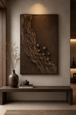 A large vertical wall art piece with a textured bronze and brown abstract design, displayed in a modern, minimalist interior setting above a dark wooden console table.