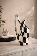 Black and white checkered pitcher on a light surface with a neutral background