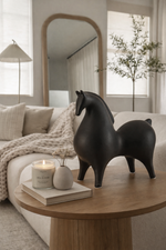 Black horse sculpture on a wooden table in a living room setting