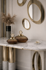 Decorative items on a marble surface with gold accents and wall mirrors.