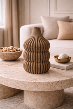 Decorative vase on a marble coffee table with a bowl of nuts and a book in a living room setting.
