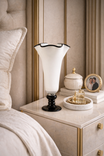 Decorative lamp on a nightstand next to a bed with pillows