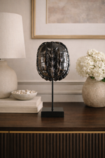 Decorative turtle shell sculpture on a stand in a home setting with a lamp and flowers.