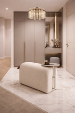 Modern interior with a beige armchair, decorative table, and wall-mounted mirror.