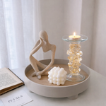 Decorative setup with a sculpture, candle holder, and book on a table.