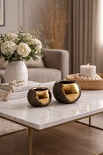 Decorative items on a marble table including vases, candles, and books with a neutral background.