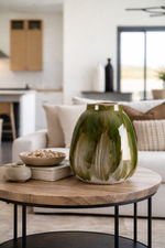 Green ceramic vase on a wooden coffee table in a living room setting