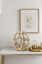Decorative table with a textured vase, framed artwork, and gold accents.