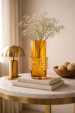 Decorative scene with an orange vase, books, and a lamp on a marble table.