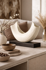 Decorative setting with a white ceramic bowl, brown bowls, and vases on a table.