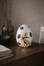 Decorative egg with gold rabbit on a wooden surface