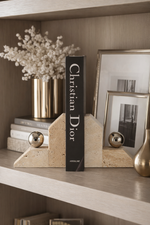 Decorative shelf with books, a vase of flowers, and framed pictures.