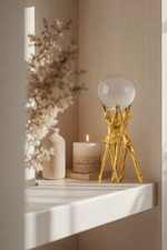 Decorative shelf with a gold sculpture, candle, and dried flowers.