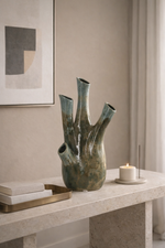 Decorative vase on a table with a candle and books in a room setting