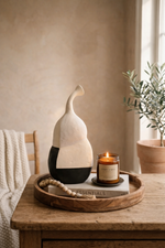 Decorative items on a wooden tray including a vase, candle, and plant in a home setting.