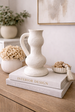 Decorative white vase on top of books with a neutral background