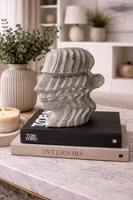 Decorative stone sculpture on books with a candle and plant in a home setting