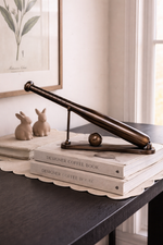 Decorative item on a stack of books with a framed picture in the background