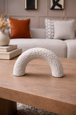 White textured arch on a wooden table with a cozy living room background