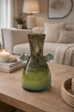 Decorative glass vase on a wooden table with a cozy living room background