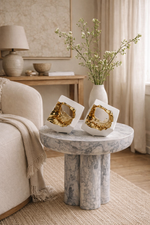 Decorative table with gold coasters and a vase of flowers in a living room setting.