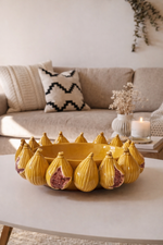 Yellow decorative bowl with fig-shaped designs on a coffee table in a living room.