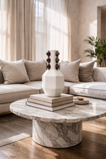 Modern living room with marble coffee table, decorative vase, and books.