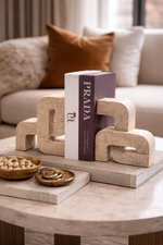 Decorative items on a coffee table with a Prada book and textured stone pieces.