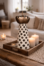 Decorative polka dot vase on a wooden tray with candles in a living room setting
