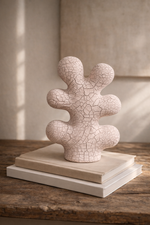 Ceramic sculpture with cracked texture on a wooden surface
