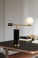 Modern table lamp with black base and gold accents on a desk.