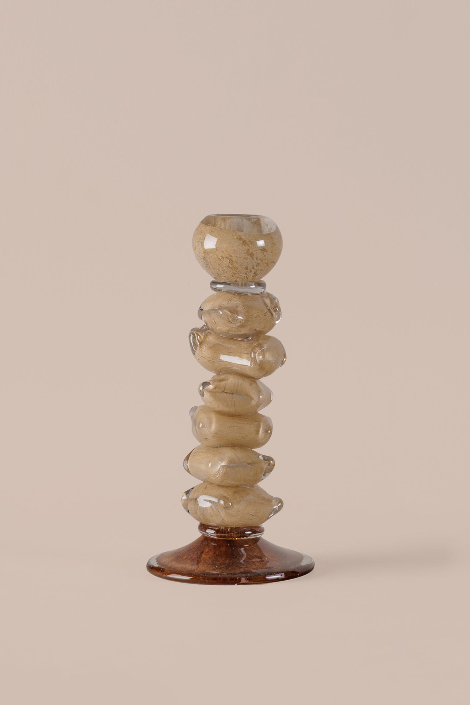 Decorative candle holder with stacked stone-like design on a beige background