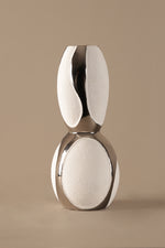 Silver and white decorative object on a beige background