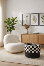 Modern living room with a white armchair, checkered ottoman, and wooden sideboard.