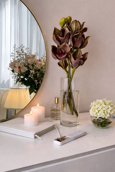 Decorative setup with flowers, candles, and a mirror on a table.