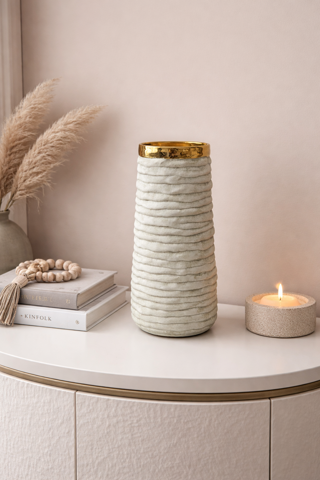 Decorative vase with gold rim on a shelf with books and a candle