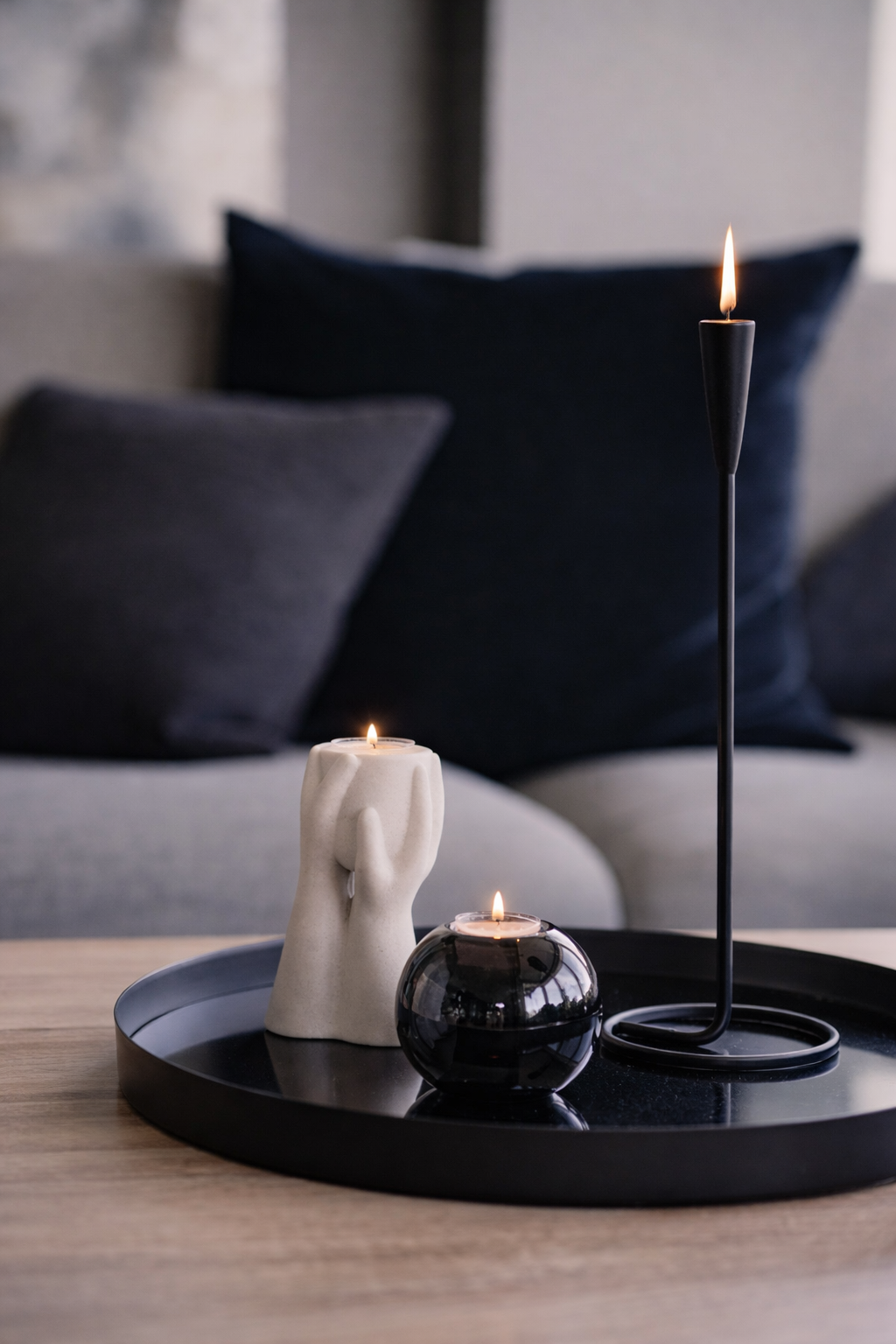 Decorative candles on a black tray with a blurred sofa in the background