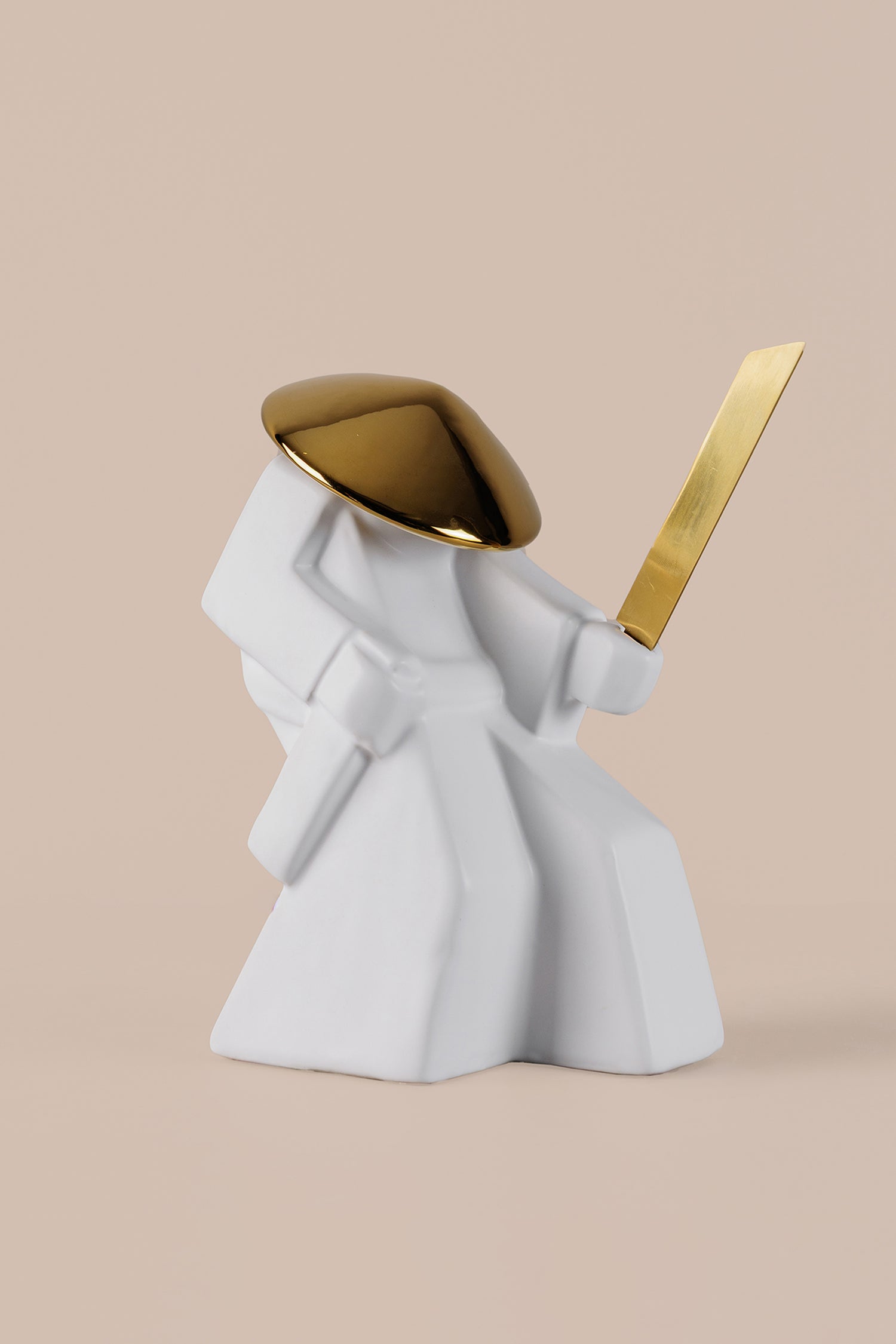 Minimalist white warrior sculpture with gold helmet and sword displayed as luxury home decor