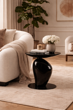 Modern living room with a black side table, beige sofa, and decorative elements.