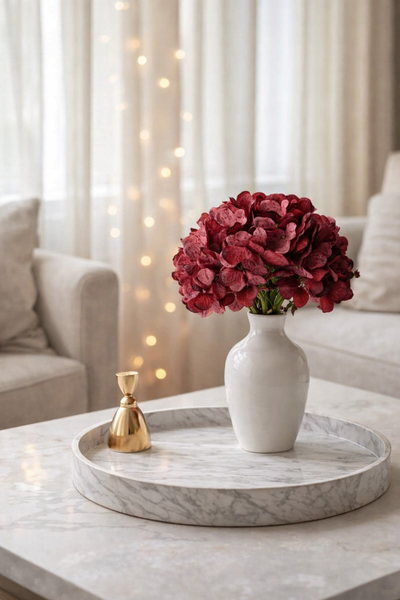 White vase with red flowers on a marble tray in a living room setting