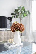 Decorative setup with a vase of flowers on a coffee table in a living room.