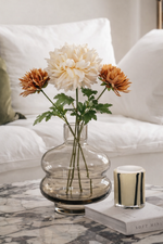 Clear glass vase with flowers on a marble surface in a living room setting