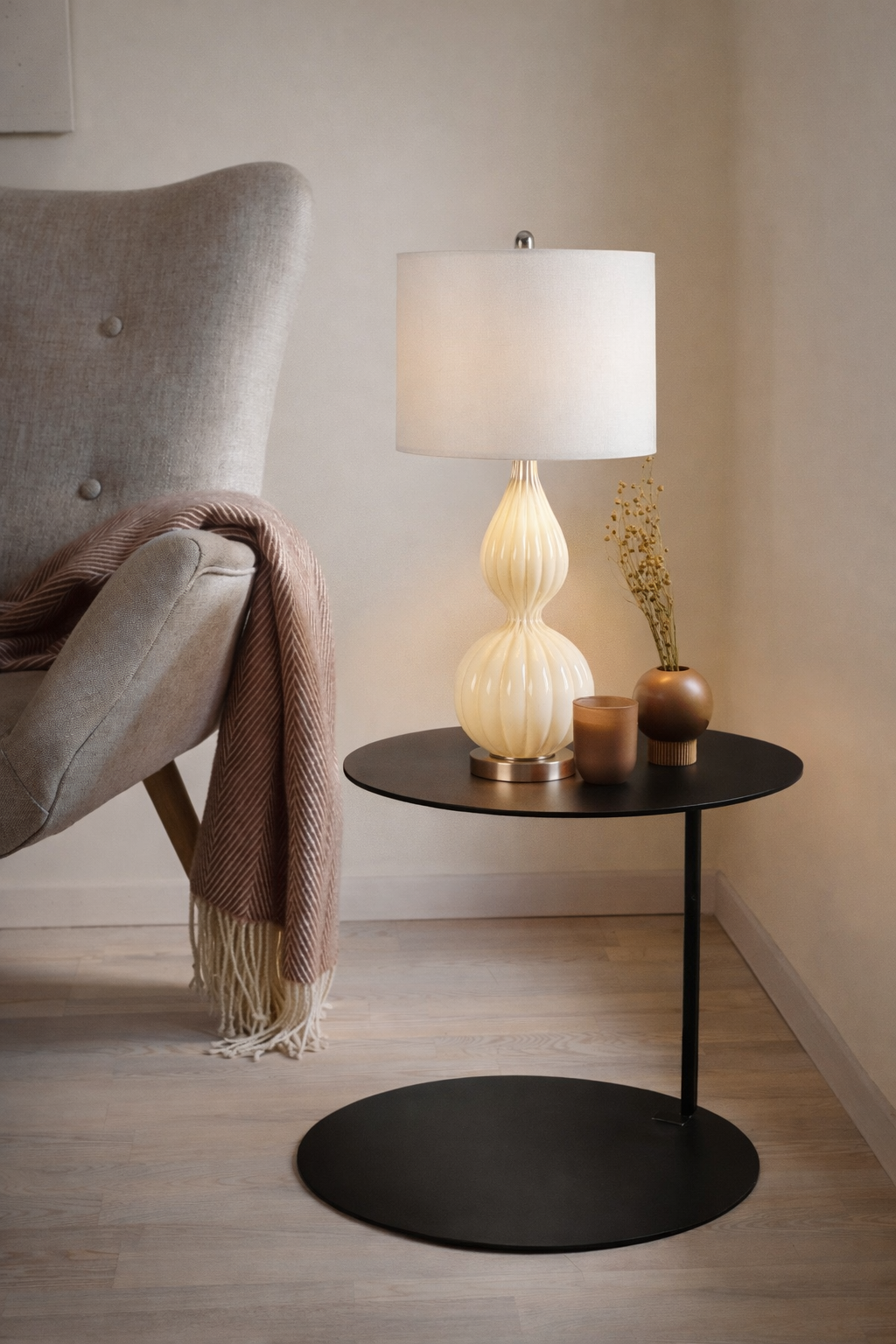 Modern interior with a black side table, white lamp, and gray armchair.